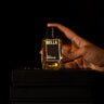 Hand holding a bottle labeled 'BELLA' on a black background